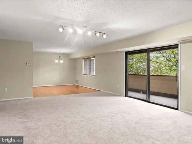 an empty room with chandelier fan and windows
