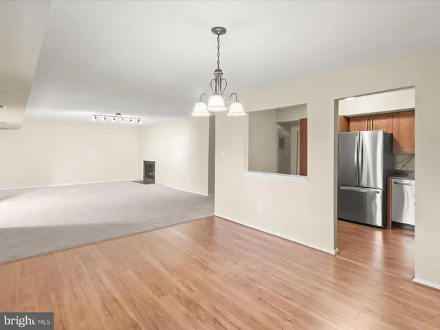 an empty room with wooden floor chandelier and windows