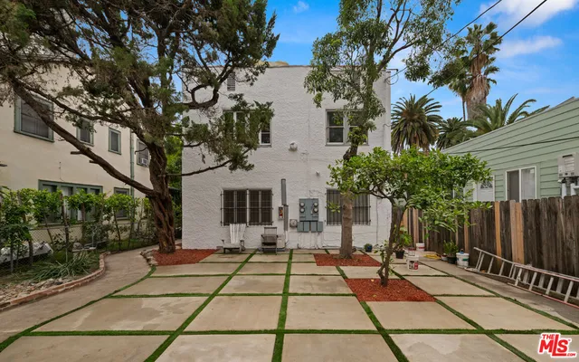 a view of a white house with a large tree