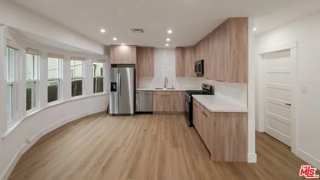 a large kitchen with stainless steel appliances granite countertop a lot of counter space and wooden floors