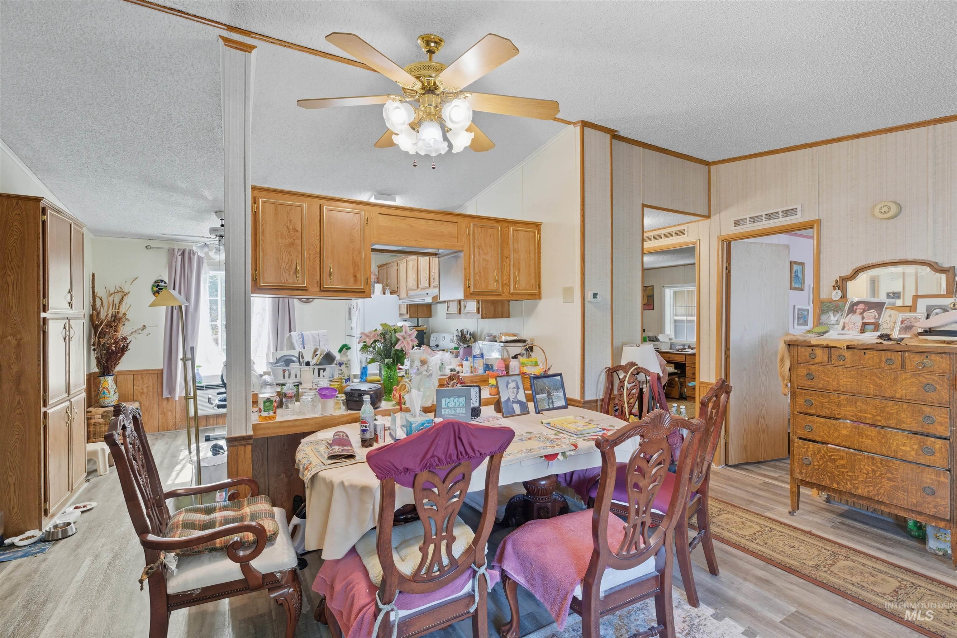 300 Main Street Deary, ID 83823 - Photo 5 of 18 Dining room with a textured ceiling, light wood-style flooring, a ceiling fan, ornamental molding, and wooden walls