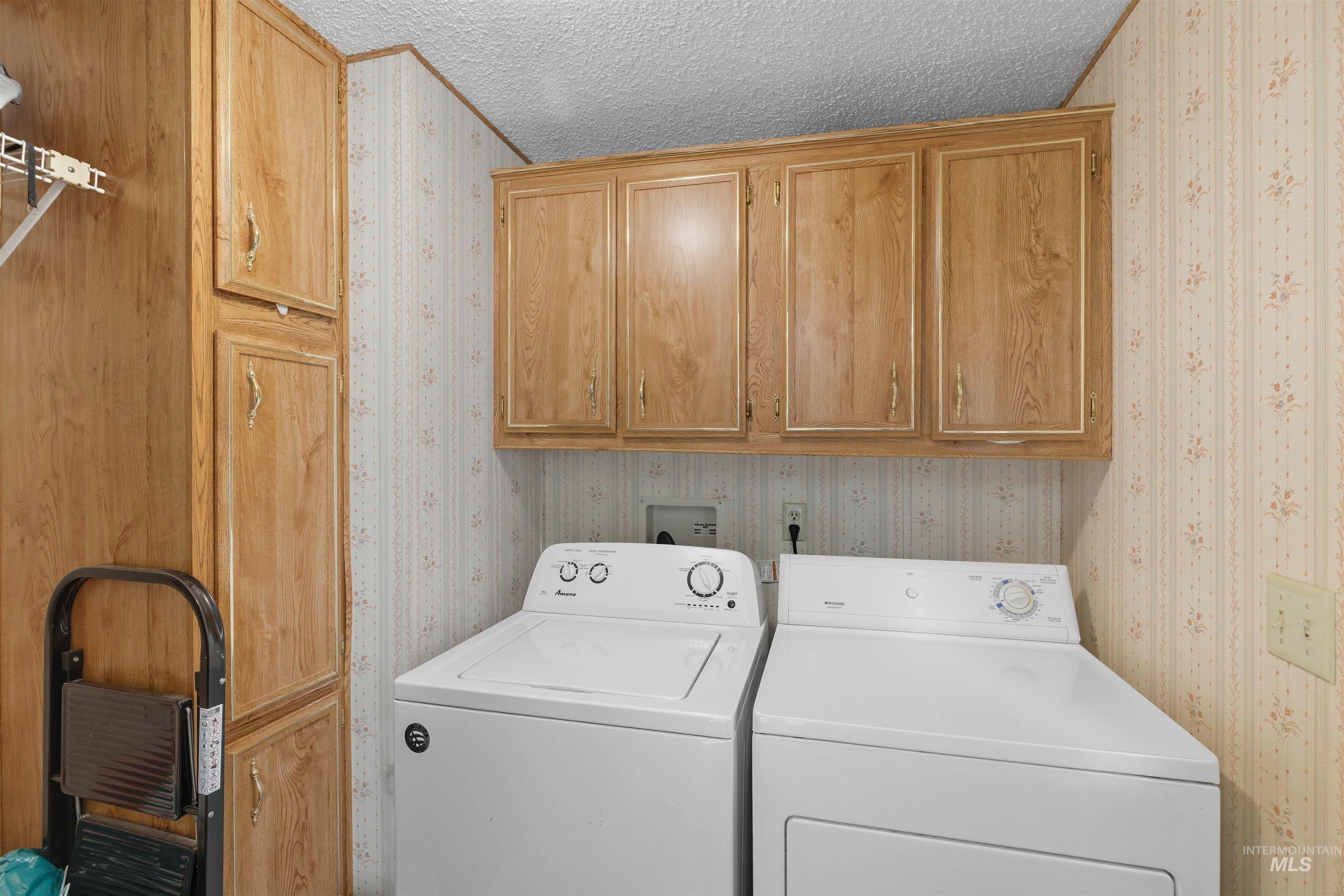300 Main Street Deary, ID 83823 - Photo 7 of 18 Laundry room featuring a textured ceiling, washer and dryer, cabinet space, and wallpapered walls