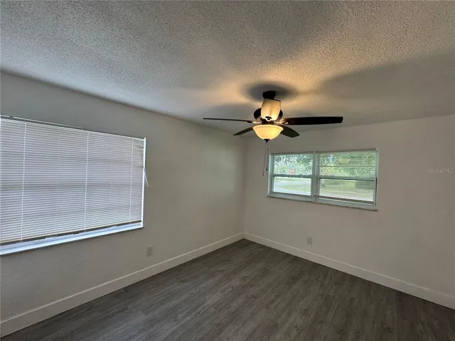 an empty room with wooden floor chandelier and windows