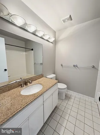 a bathroom with a granite countertop sink a toilet and a mirror