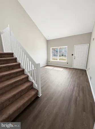 a view of an empty room with wooden floor and stairs
