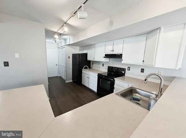 a kitchen with stainless steel appliances granite countertop a refrigerator a sink dishwasher a stove and white cabinets with wooden floor