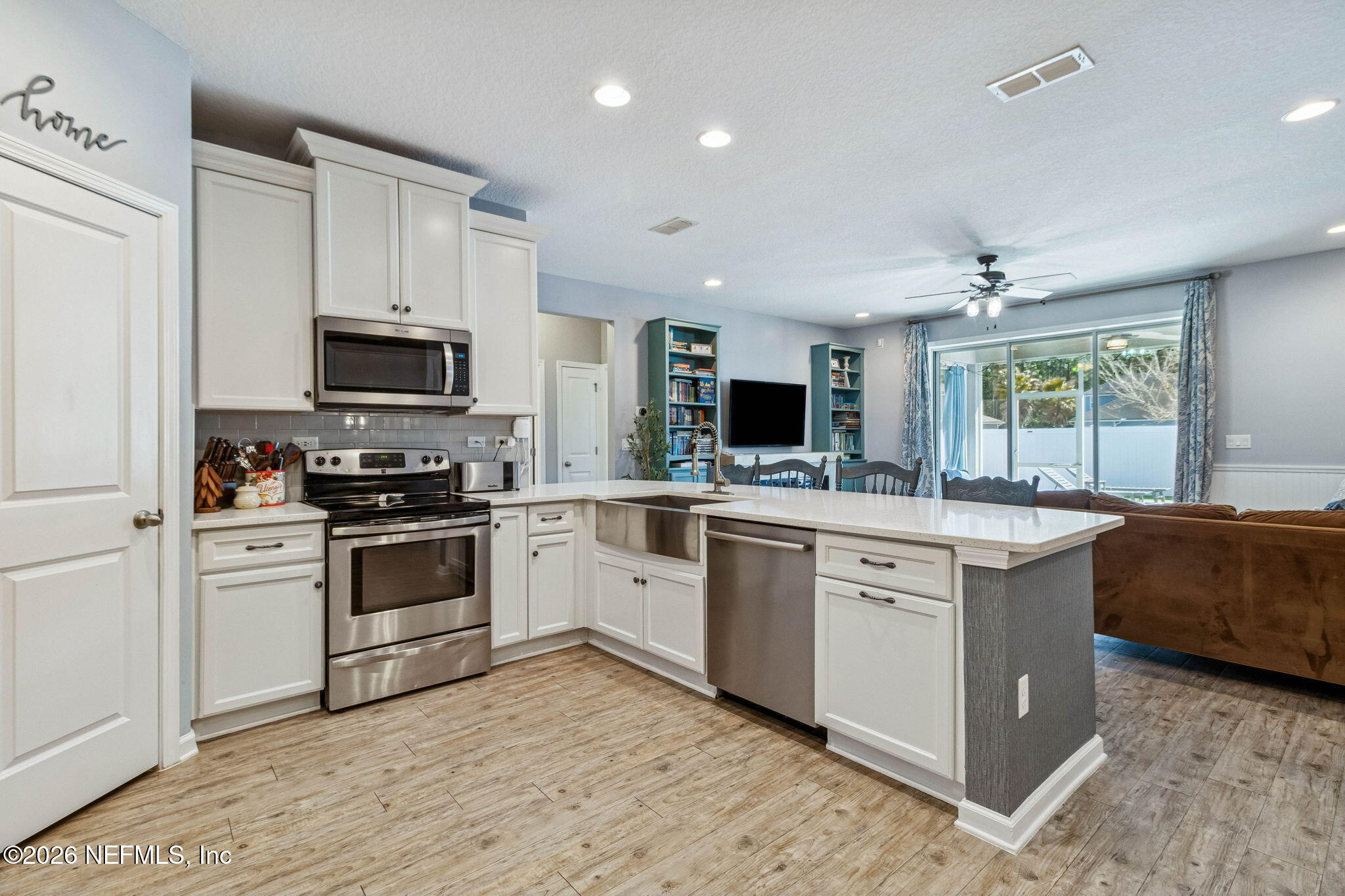 96048 Breezeway Court Yulee, FL 32097 - Photo 11 of 26 a kitchen with stainless steel appliances kitchen island granite countertop a stove a sink and a microwave