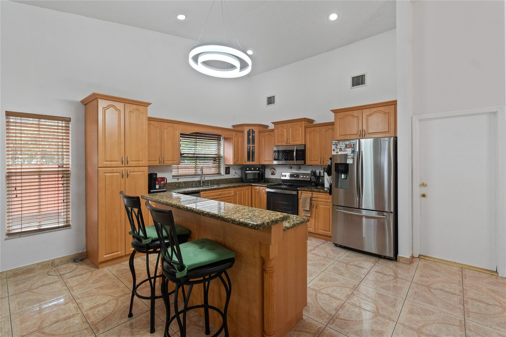 7440 Southwest 93rd Avenue Miami, FL 33173 - Photo 24 of 50 a kitchen with stainless steel appliances granite countertop a refrigerator a stove a sink a dining table and chairs with wooden floor