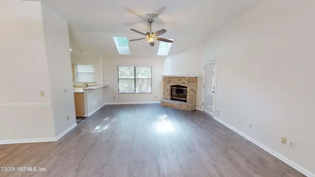 an empty room with wooden floor fireplace and windows