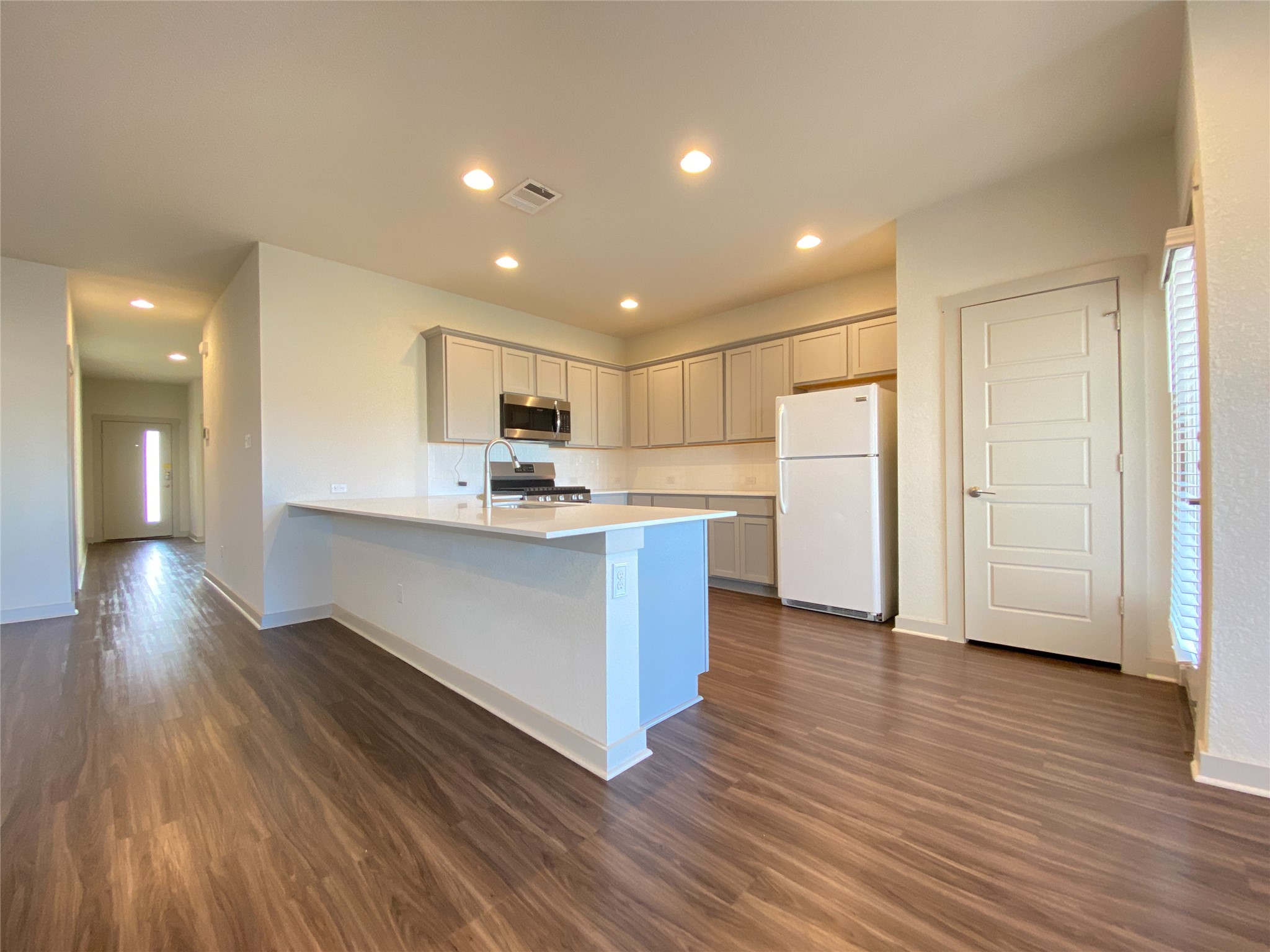 5121 Vanner Path Georgetown, TX 78626 - Photo 5 of 24 a kitchen with stainless steel appliances kitchen island wooden floors wooden cabinets and entryway