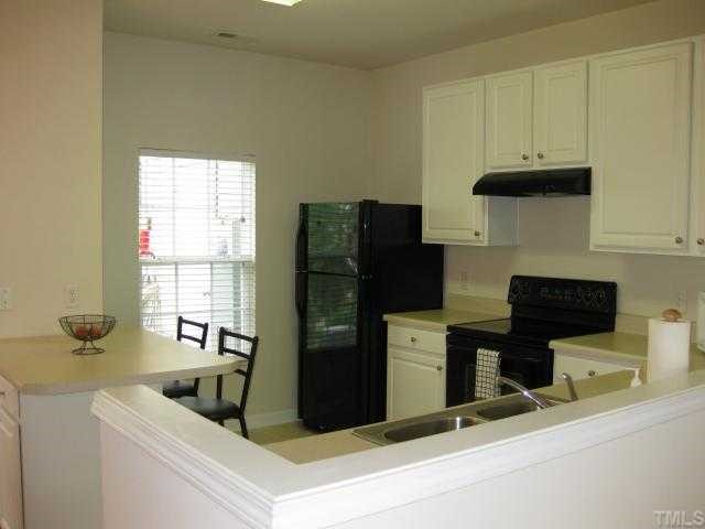 8131 Rhiannon Road Raleigh, NC 27613 - Photo 3 of 12 Open kitchen with breakfast bar, black appliances (refrigerator conveys), smooth top stove, neutral counter tops, breakfast bar, and pantry.