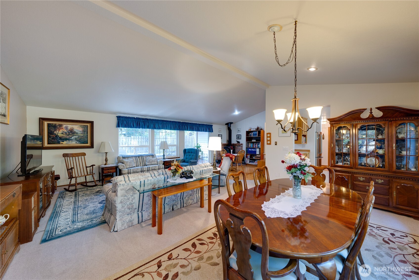 399 Tilingit Place La Conner, WA 98257 - Photo 7 of 39 a view of a dining room and livingroom with furniture wooden floor a rug a flat screen tv a painting and a chandelier