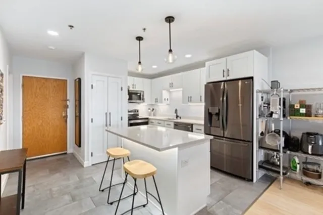 a kitchen with stainless steel appliances a refrigerator a sink dishwasher a stove a dining table and chairs