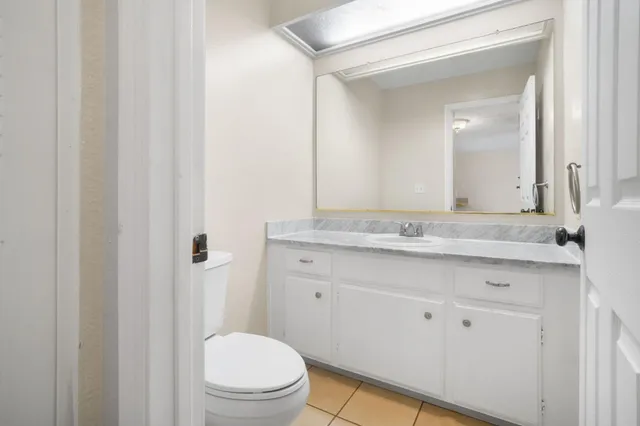 a bathroom with a granite countertop sink toilet and mirror