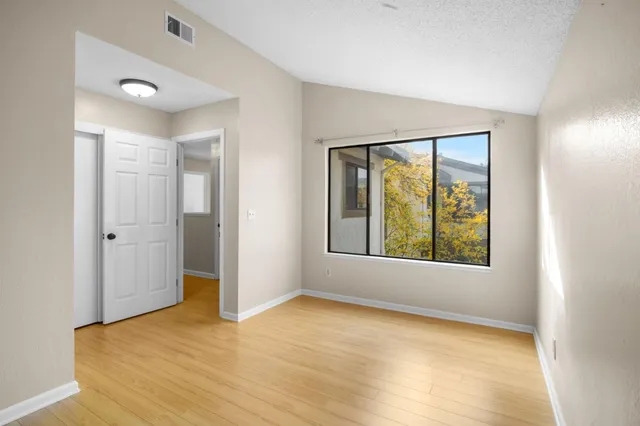 a view of an empty room with window and wooden floor
