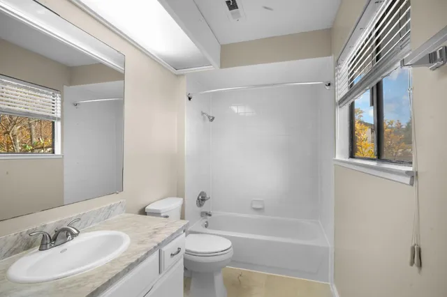 a bathroom with a granite countertop sink a toilet a mirror and bathtub