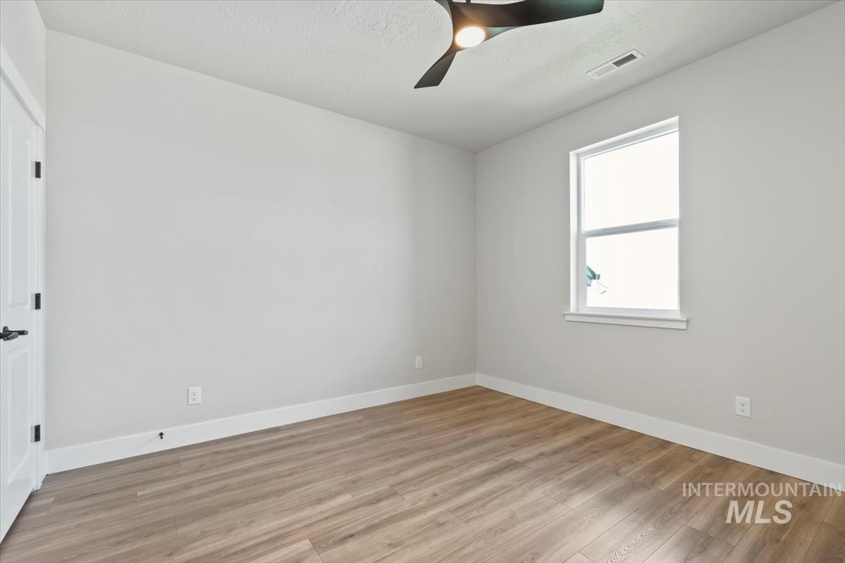 2830 West Jutland Street Meridian, ID 83642 - Photo 18 of 40 Empty room featuring light wood-style flooring, a ceiling fan, and a textured ceiling