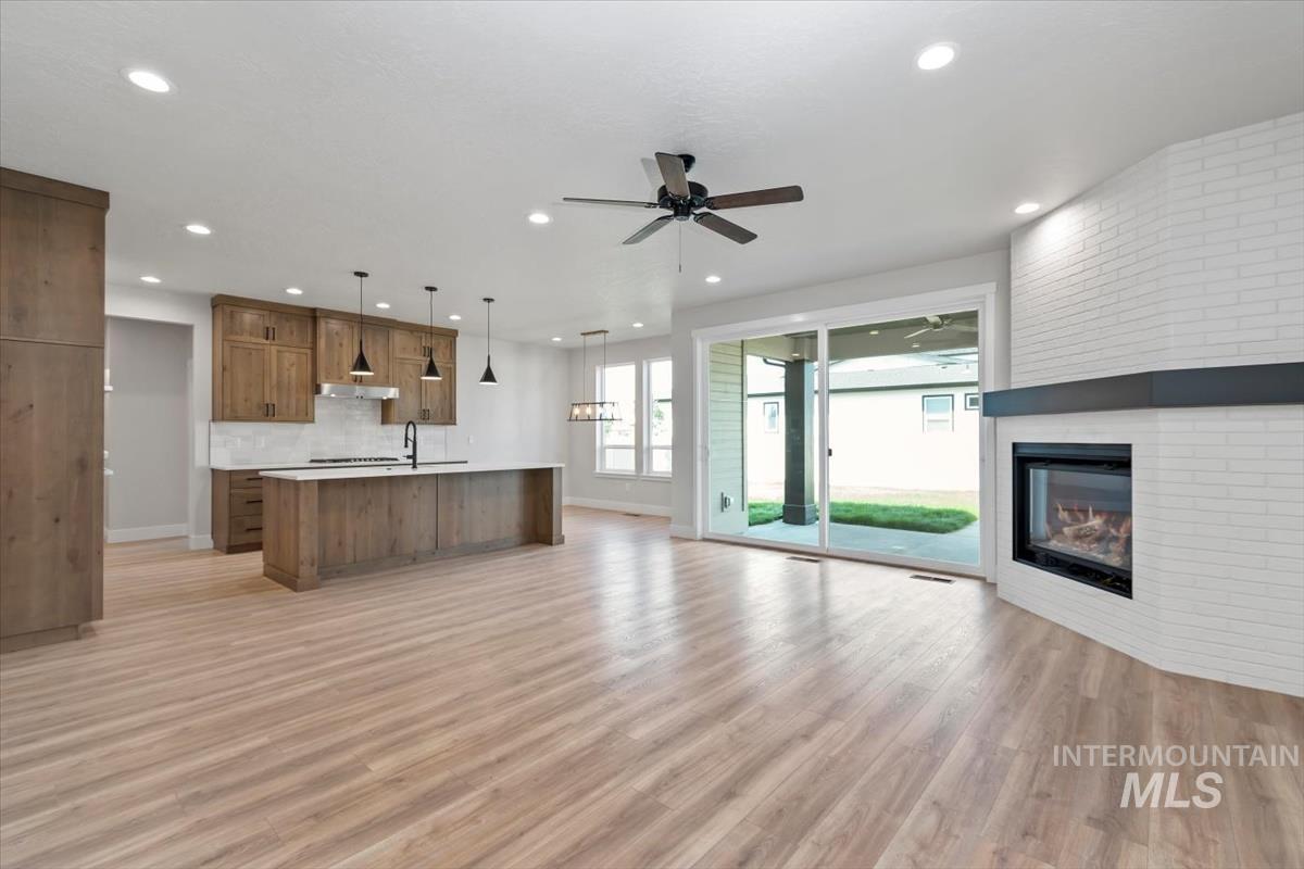 2830 West Jutland Street Meridian, ID 83642 - Photo 2 of 40 Unfurnished living room featuring light wood-style floors, a large fireplace, a ceiling fan, and recessed lighting