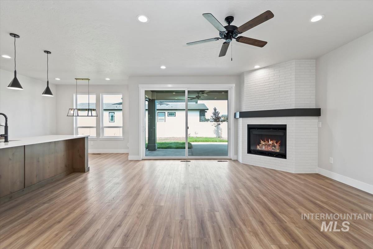 2830 West Jutland Street Meridian, ID 83642 - Photo 3 of 40 Unfurnished living room featuring a brick fireplace, light wood-type flooring, recessed lighting, and a ceiling fan