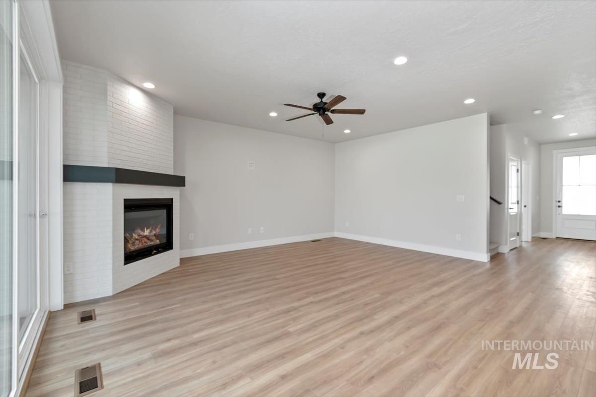 2830 West Jutland Street Meridian, ID 83642 - Photo 5 of 40 Unfurnished living room with light wood-type flooring, a fireplace, recessed lighting, and ceiling fan