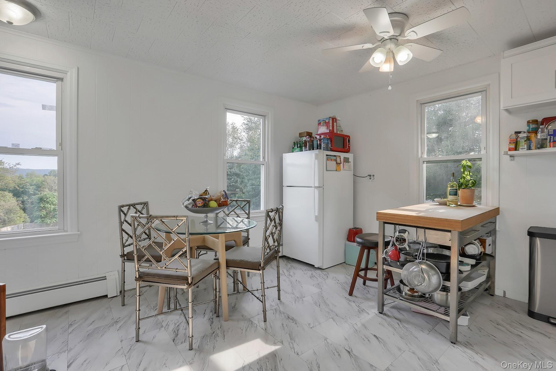 71 Greycourt Road Chester, NY 10918 - Photo 19 of 38 Dining area featuring a baseboard heating unit, light marble finish flooring, healthy amount of natural light, and ceiling fan
