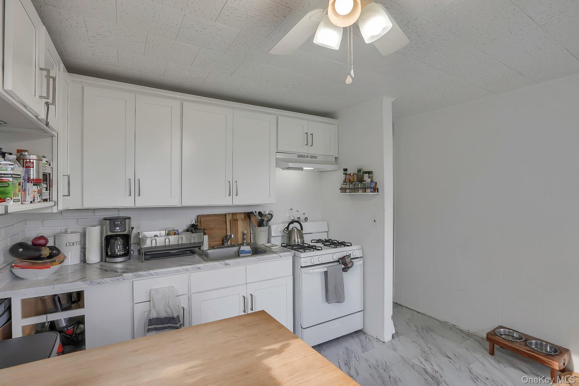 71 Greycourt Road Chester, NY 10918 - Photo 22 of 38 Kitchen featuring white gas range, white cabinets, light countertops, under cabinet range hood, and ceiling fan