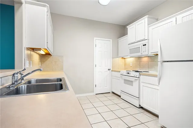 a kitchen with a sink a stove and white cabinets