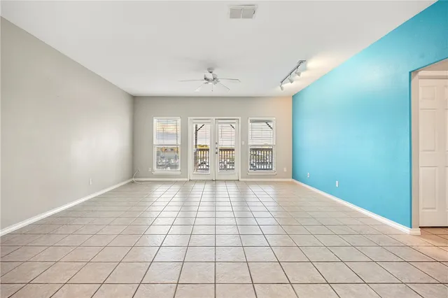 a view of an empty room with window and chandelier fan