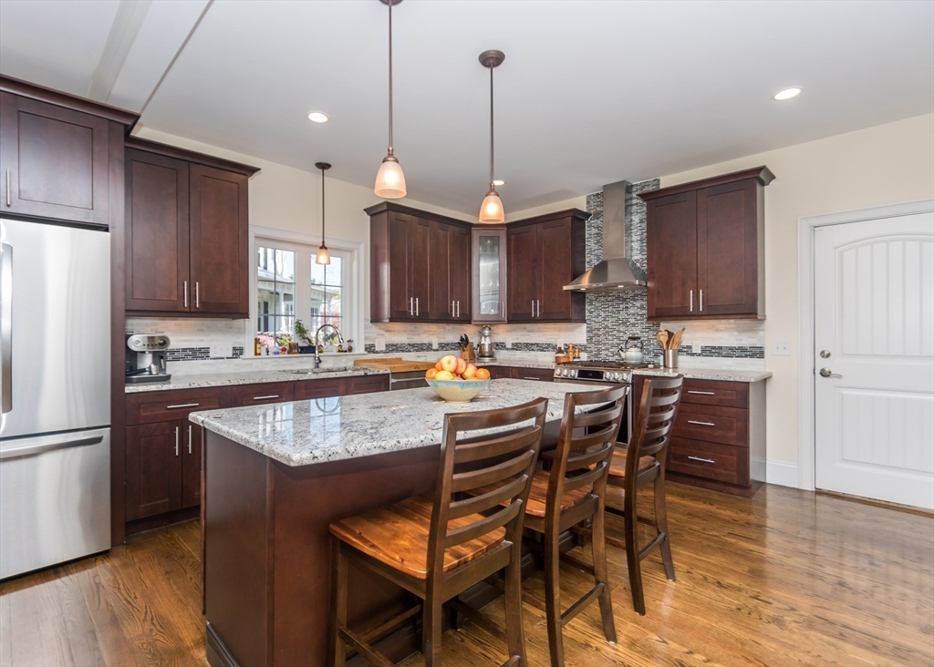 128 Church Street, Unit 2 Waltham, MA 02452 - Photo 15 of 41 a kitchen with stainless steel appliances granite countertop a table chairs refrigerator and a sink