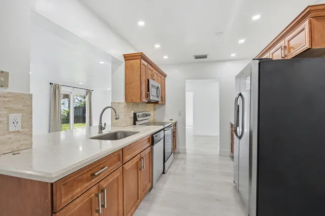 a kitchen with stainless steel appliances granite countertop a refrigerator and a sink