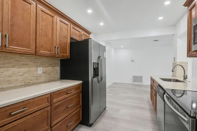 a kitchen with stainless steel appliances granite countertop a refrigerator and a sink