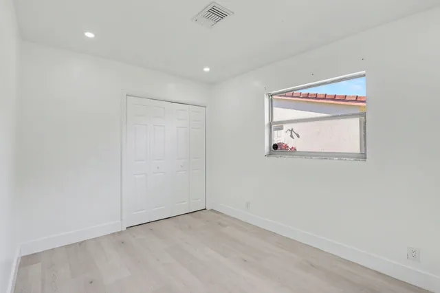 an empty room with wooden floor and fan
