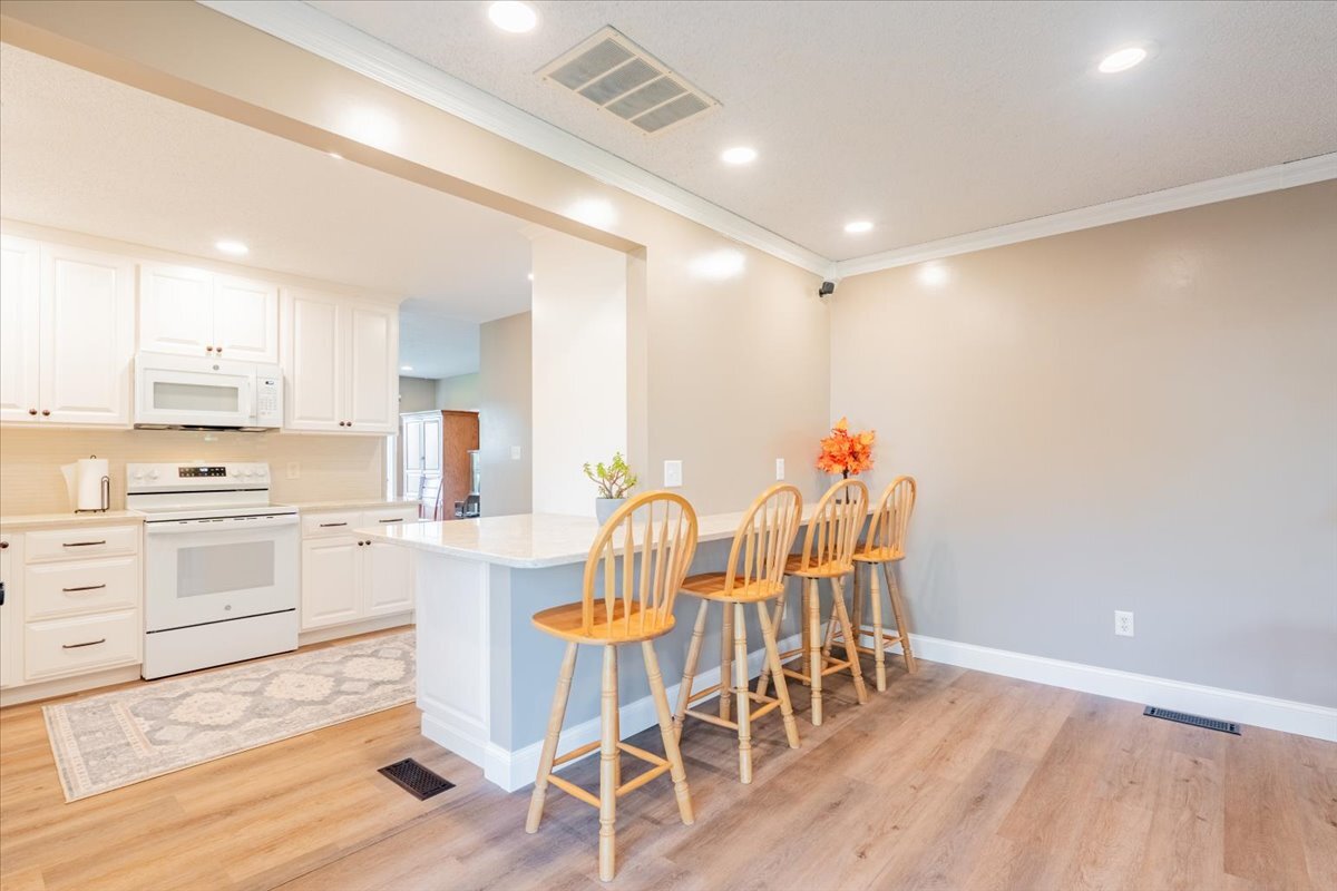 16 Holly Drive Clinton, IL 61727 - Photo 13 of 34 a kitchen with stainless steel appliances kitchen island granite countertop a stove a refrigerator and white cabinets with wooden floor