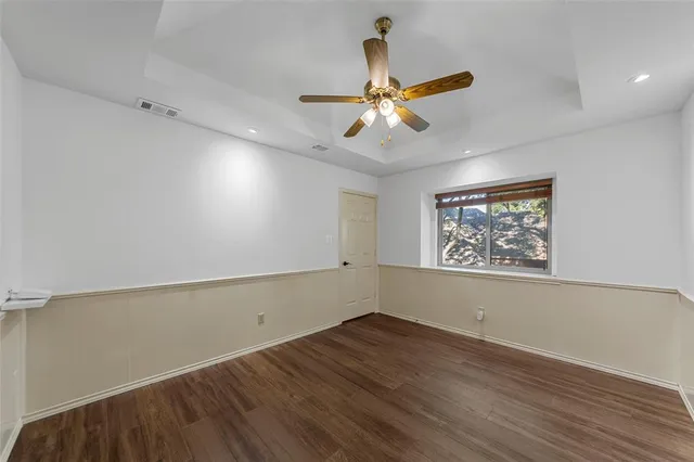 an empty room with wooden floor fan and windows