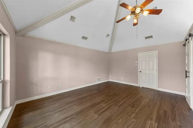an empty room with wooden floor fan and windows
