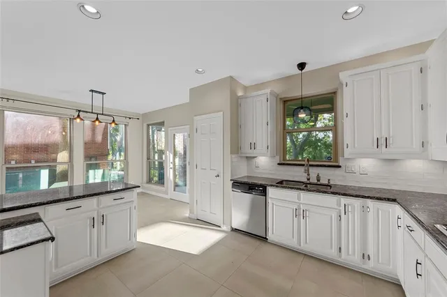 a large white kitchen with granite countertop a sink and white cabinets
