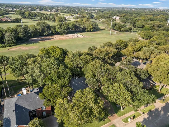 an aerial view of residential houses with outdoor space and trees