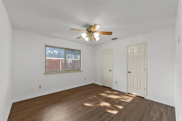 a view of an empty room with a window and a chandelier fan