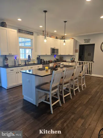 a kitchen with stainless steel appliances granite countertop a table chairs sink and cabinets