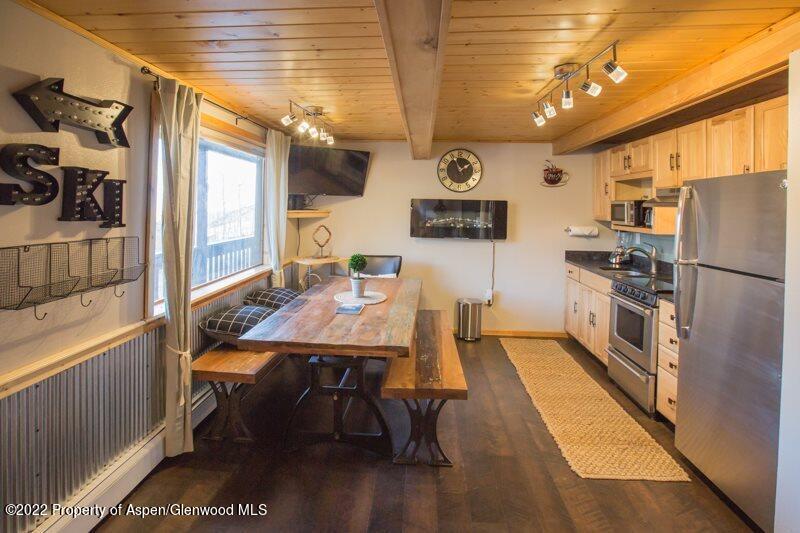 a kitchen with stainless steel appliances a stove a refrigerator and a dining table with wooden floor