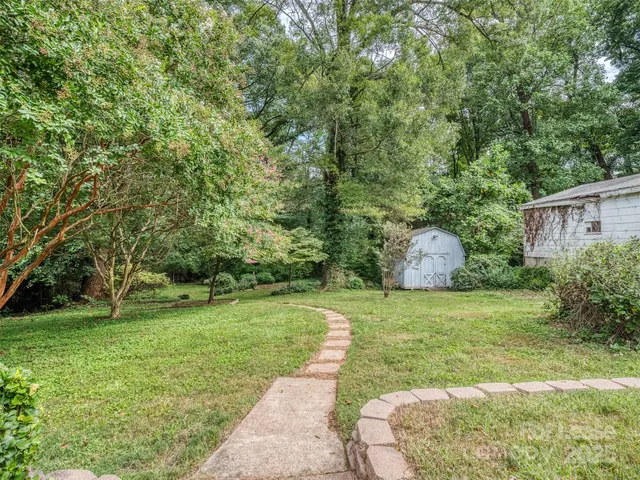 a backyard of a house with plants and large trees
