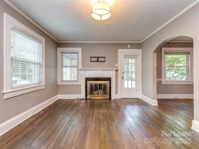 an empty room with wooden floor a fireplace and windows