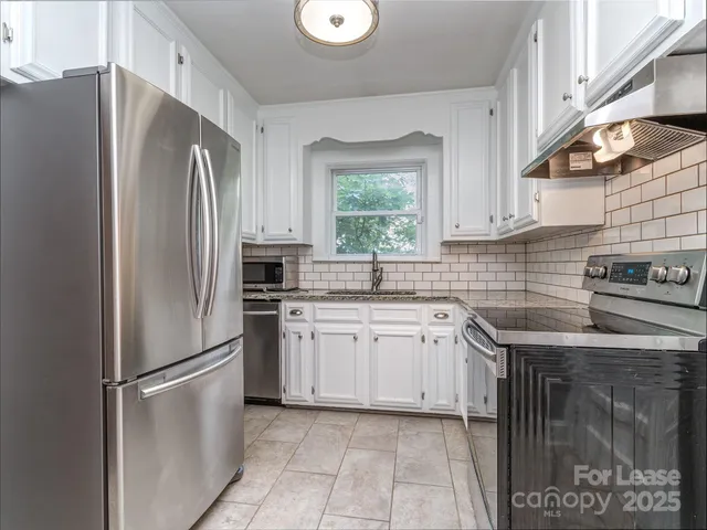 a kitchen with stainless steel appliances granite countertop a refrigerator a sink a stove and washer