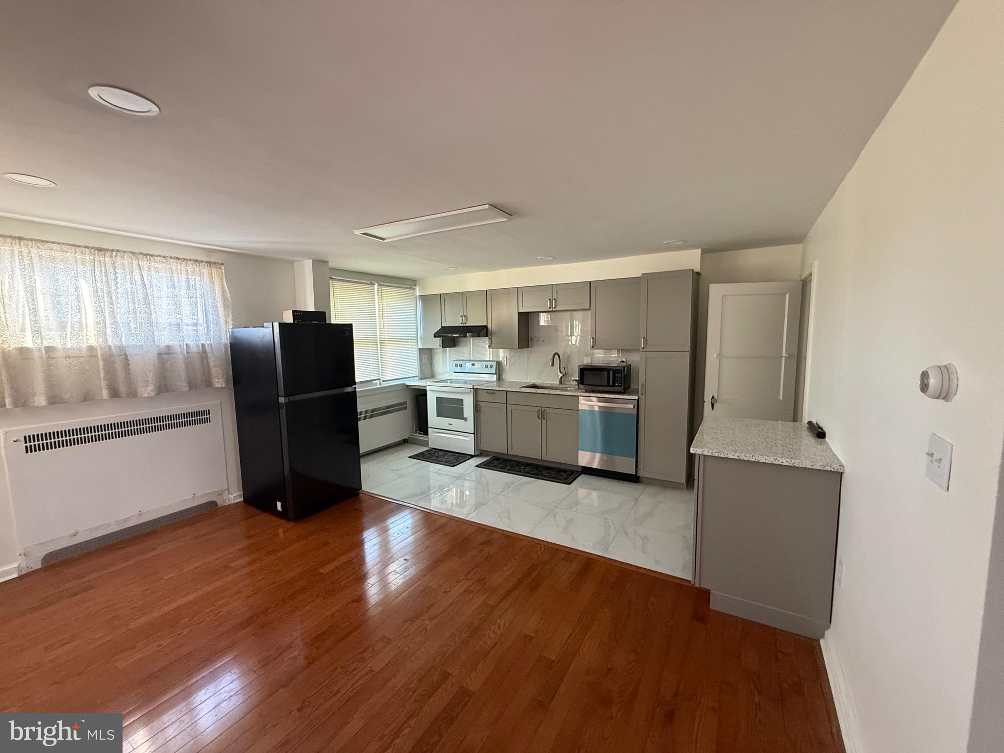 363 Sherbrook Boulevard Upper Darby, PA 19082 - Photo 4 of 12 a kitchen with stainless steel appliances wooden floors and wooden cabinets