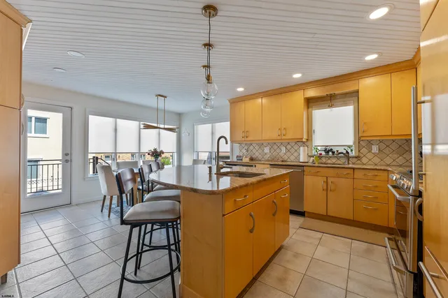 a kitchen with stainless steel appliances granite countertop a stove refrigerator a dining table and chairs with wooden floor