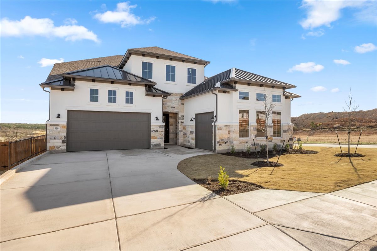 View of front of home featuring metal roof, concrete driveway, a standing seam roof, and an attached garage