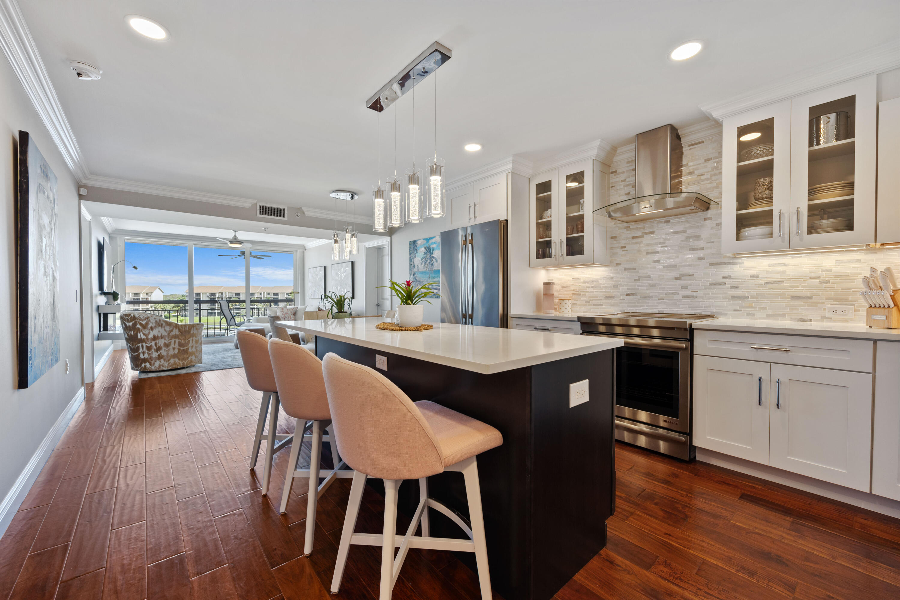 2401 Marina Isle Way, Unit 503 Jupiter, FL 33477 - Photo 5 of 30 a kitchen with stainless steel appliances granite countertop a stove a sink dishwasher a dining table and chairs with wooden floor