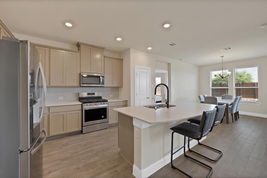 10401 Table Blf Street Aubrey, TX 76227 - Photo 2 of 25 a kitchen with kitchen island a stove a sink and a refrigerator
