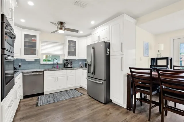 a kitchen with granite countertop a refrigerator a stove a sink and a dining table with wooden floor