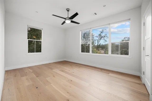 a view of an empty room with a window and wooden floor